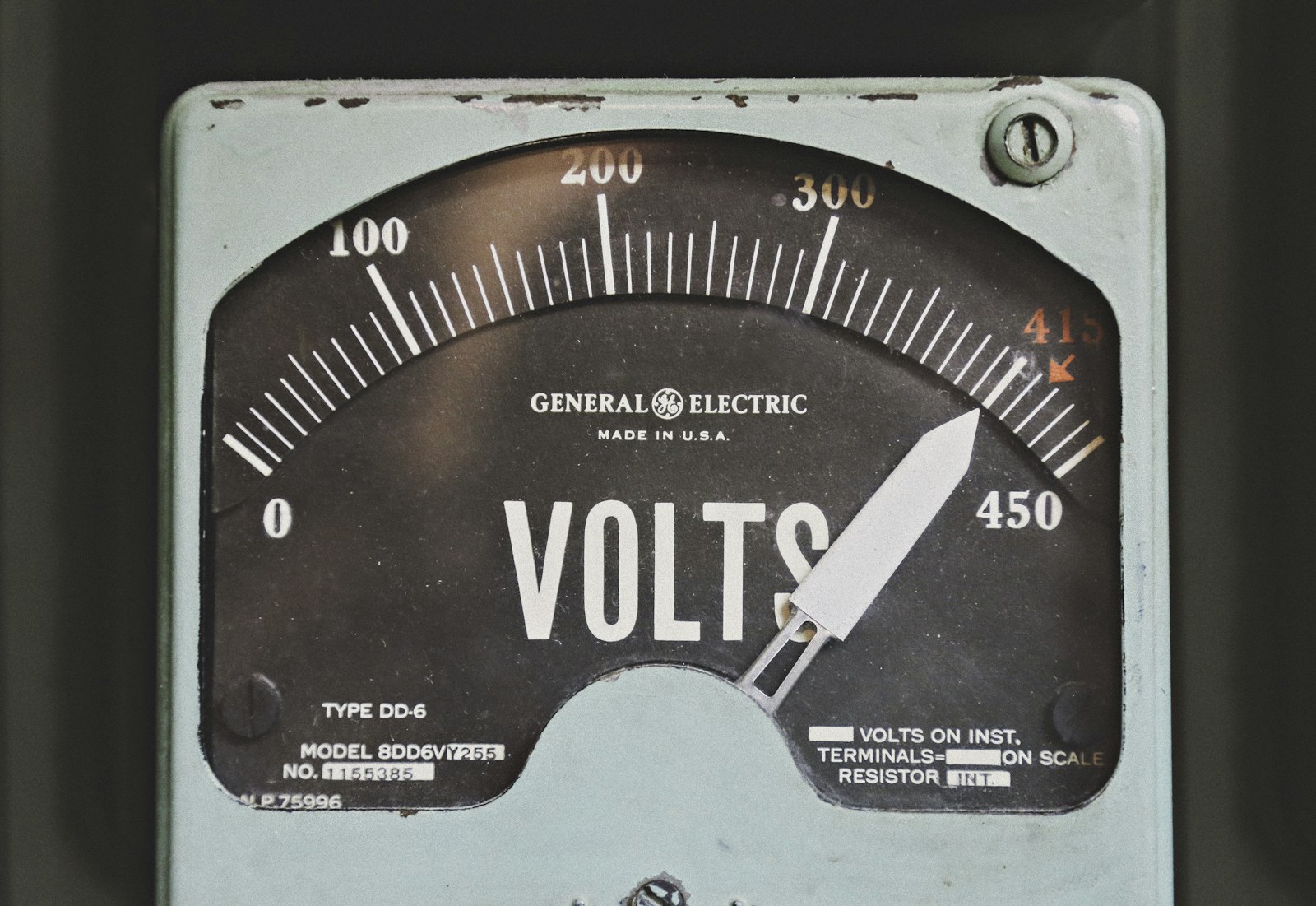 A gray GE volt meter mounted on a wall
