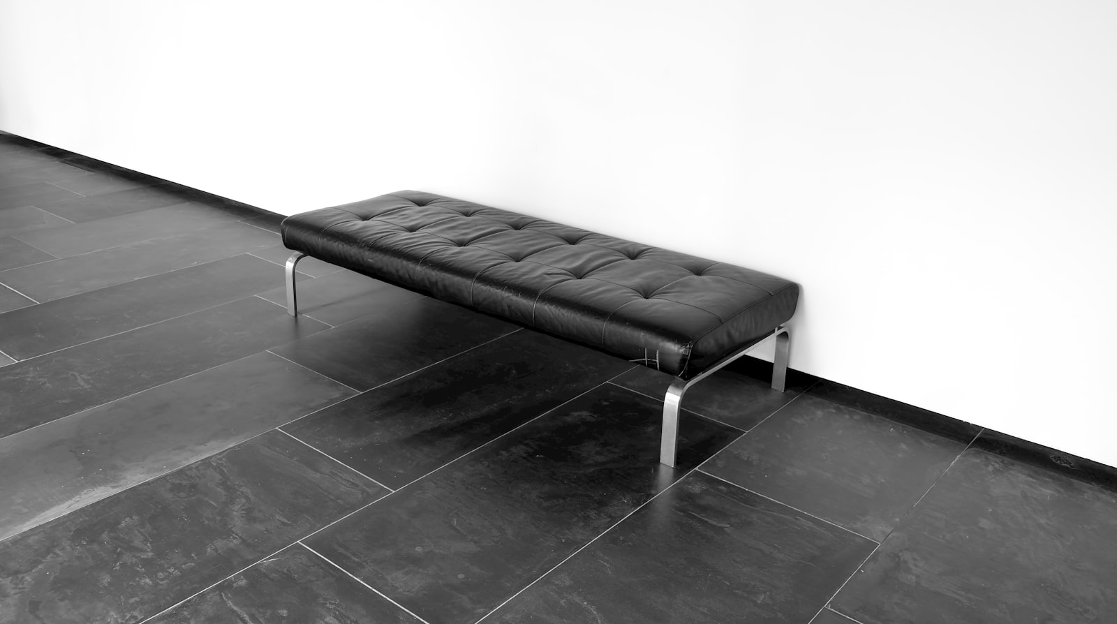 A black leather bench on a tiled floor in a modern office